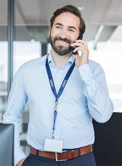Dark haired man with beard and blue shirt talking on phone