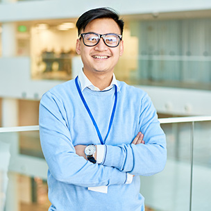 A smartly dressed man crossing his arms and smiling at the camera
