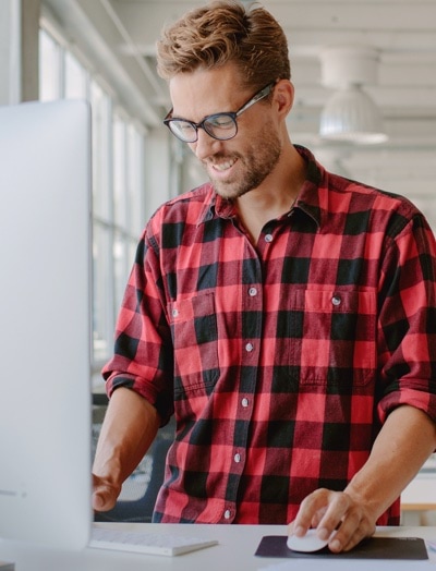 Man in flannel shirt working on his computer, checking his G Suite account