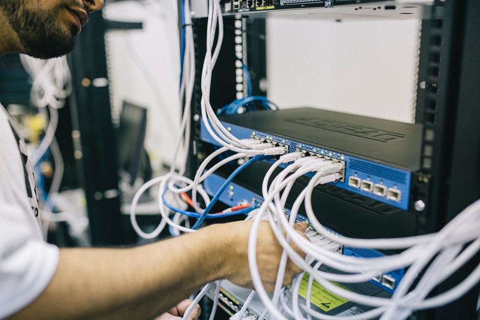 Technician inserting cables into a rack of servers